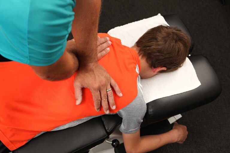 A resident stretching their neck while seated at a desk with natural daylight in the background.